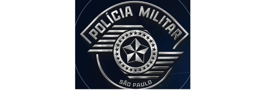 Policiais militares do BAEP, da PM de SP, estão posicionados ao lado de uma viatura oficial com as portas abertas. Os agentes estão fardados e atentos, com o prédio da corporação e a bandeira do Brasil ao fundo, em um cenário de prontidão e disciplina.
