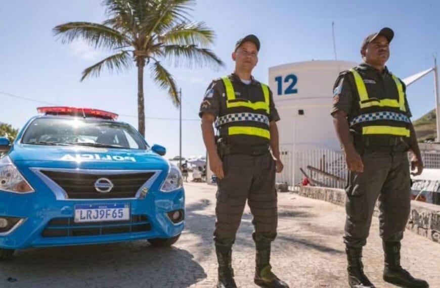 Serviço voluntário: Dois policiais militares do Rio de Janeiro em serviço à beira-mar, ao lado de viatura da PMERJ, usando coletes reflexivos em frente ao posto 12.