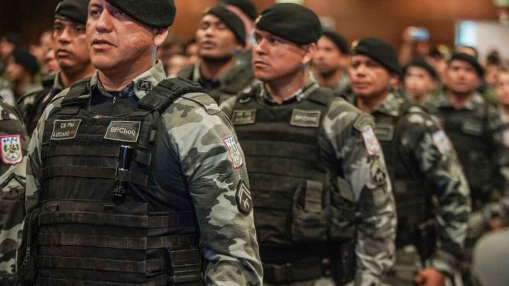 Policiais militares fardados do Batalhão de Choque participam de uma solenidade; todos usam boina preta e uniforme camuflado, alinhados em formação.