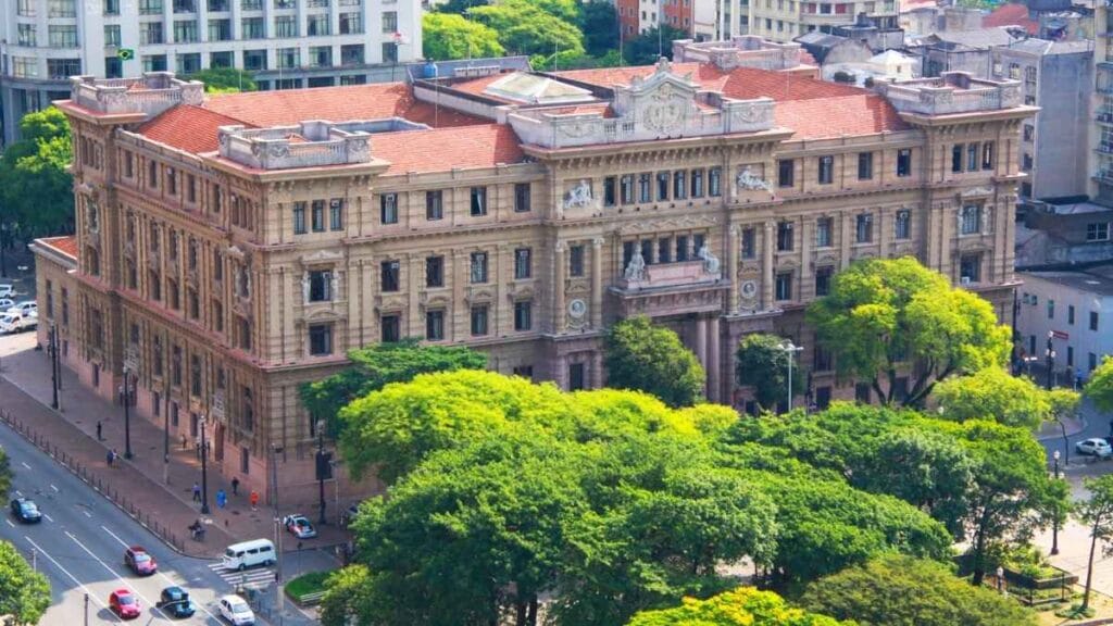 Polícia Municipal: Fachada do Palácio da Justiça de São Paulo, sede do Tribunal de Justiça do Estado, vista aérea com árvores ao redor e movimentação de pedestres e veículos nas ruas próximas.
