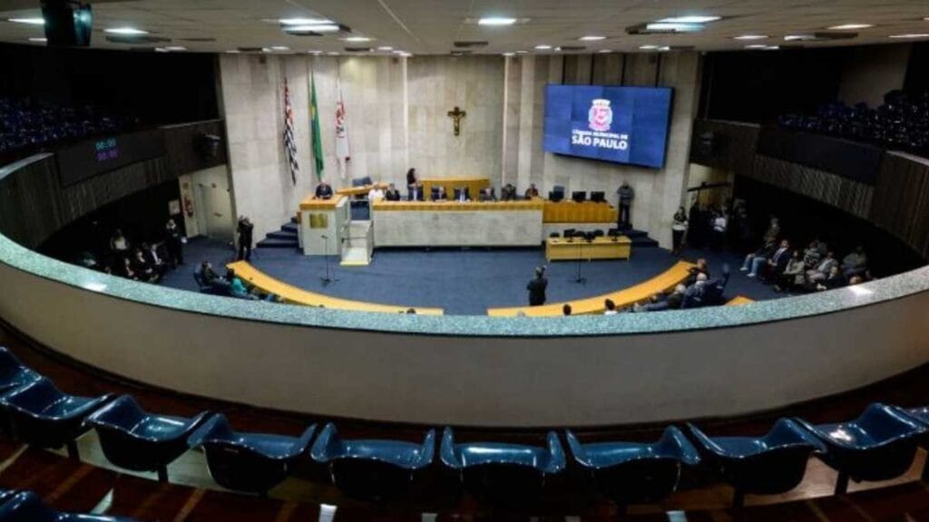 GCM de SP cria bônus para quem recuperar moto -Plenário da Câmara Municipal de São Paulo durante sessão, com vereadores reunidos na mesa diretora e cadeiras vazias no auditório