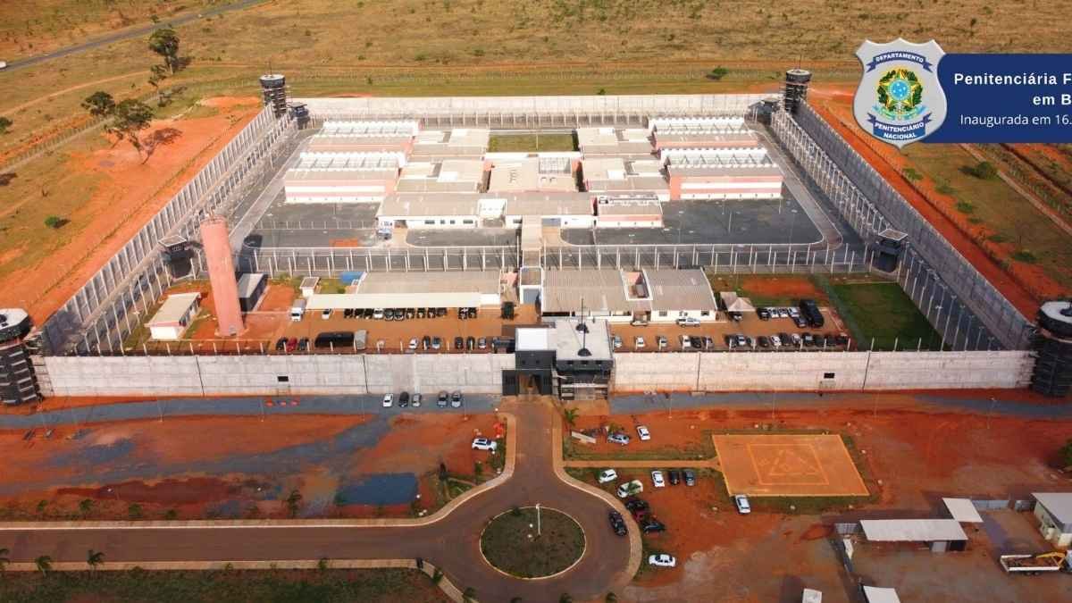 Questão de tabletes demonstra ago mais: Vista aérea da Penitenciária Federal em Brasília, inaugurada em 16 de outubro de 2018. A imagem mostra a estrutura de segurança máxima com torres de vigilância, muros altos, áreas isoladas e pátios internos. A unidade é cercada por terrenos amplos e possui controle rigoroso de acesso, com várias viaturas estacionadas na parte externa.