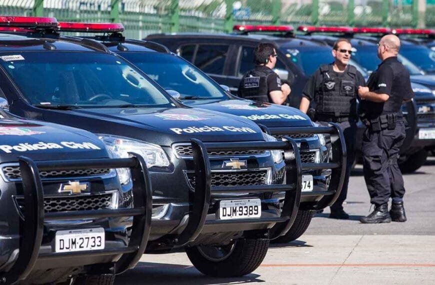 Lei orgânica da PCSP: Viaturas da Polícia Civil de São Paulo estacionadas lado a lado, com policiais em uniforme conversando próximos aos veículos.