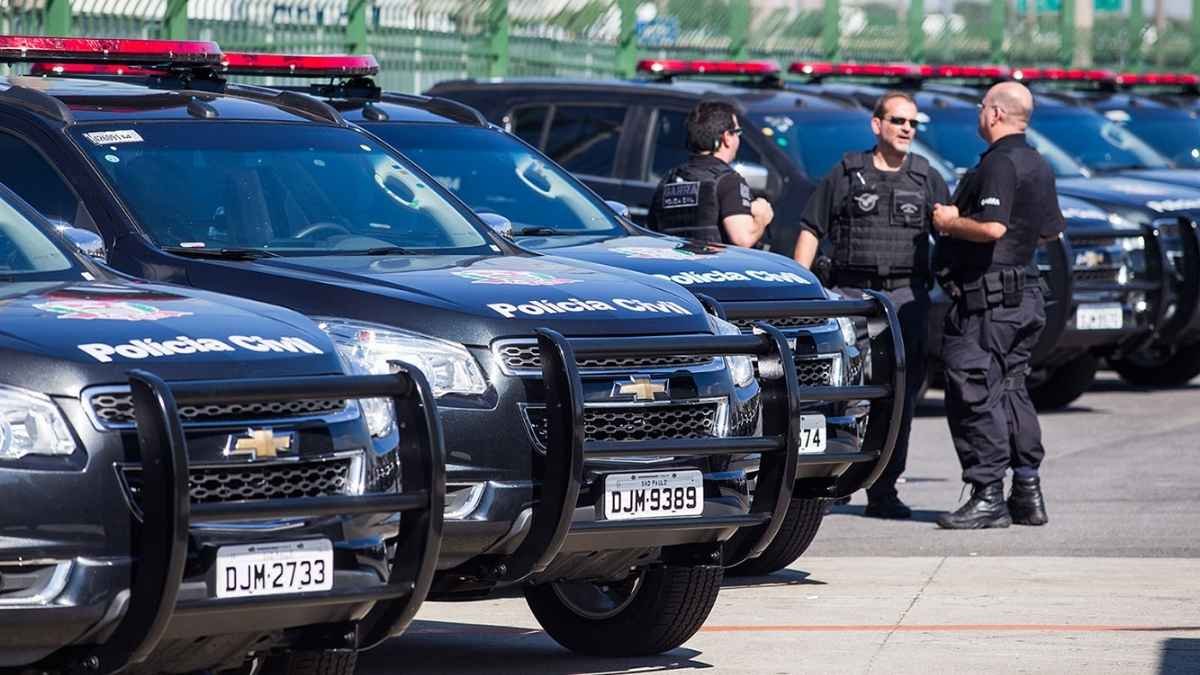 Lei orgânica da PCSP: Viaturas da Polícia Civil de São Paulo estacionadas lado a lado, com policiais em uniforme conversando próximos aos veículos.