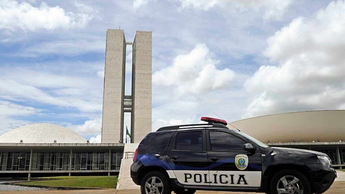 Polícia Legislativa Federal: Imagem mostra uma viatura policial preta, estacionada em frente ao Congresso Nacional, em Brasília, com as cúpulas e as torres do prédio ao fundo sob um céu parcialmente nublado.