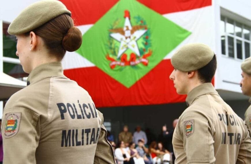 soldado e bombeiro temporário: Imagem mostra policiais militares de Santa Catarina, uniformizados e perfilados, com a bandeira do estado ao fundo.