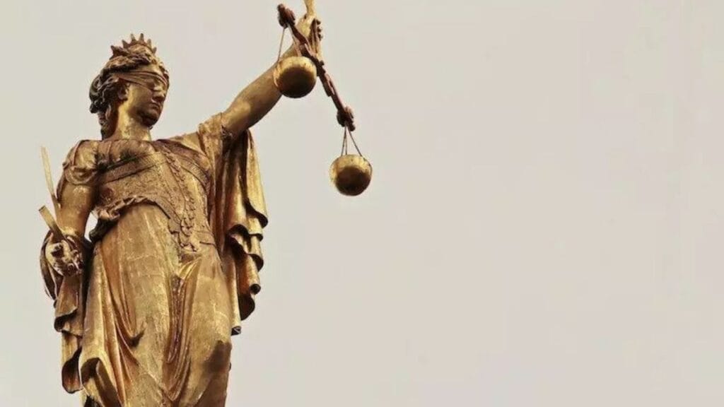 Audiências de custódia: necessárias ou lenientes com o crime? - Justiça frágil: Estátua dourada da deusa da justiça, com venda nos olhos, segurando uma balança em uma mão e uma espada na outra