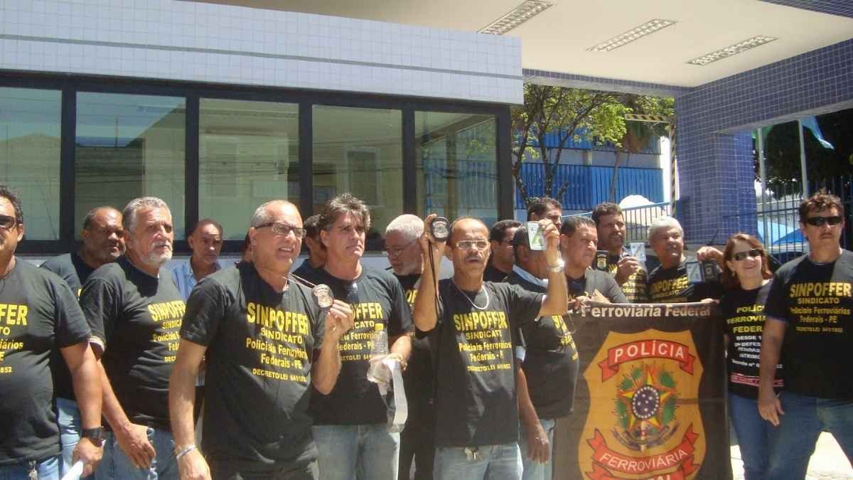 Polícia Ferroviária Federal: a polícia esquecida - Grupo de policiais ferroviários federais em manifestação, usando camisetas pretas do sindicato (SINPOFFER) e exibindo carteiras funcionais em frente a um prédio público.