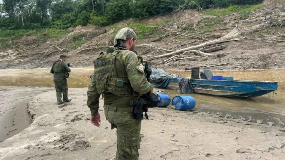 Resumo em texto alt para a matéria: **Texto alt:** Mapa da Amazônia com destaque para áreas em vermelho sob influência do narcotráfico. Ícones representam rotas de drogas, garimpo ilegal e exploração de madeira. Pequenas comunidades indígenas e ribeirinhas aparecem cercadas, simbolizando a ameaça às populações tradicionais.