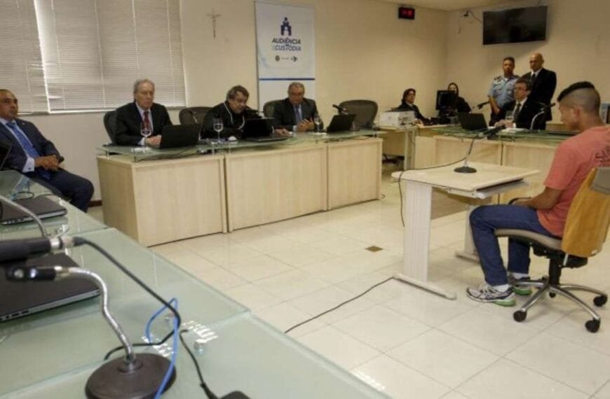 Audiência de custódia no tribunal, com juiz, advogados, representantes do Ministério Público e réu presente.