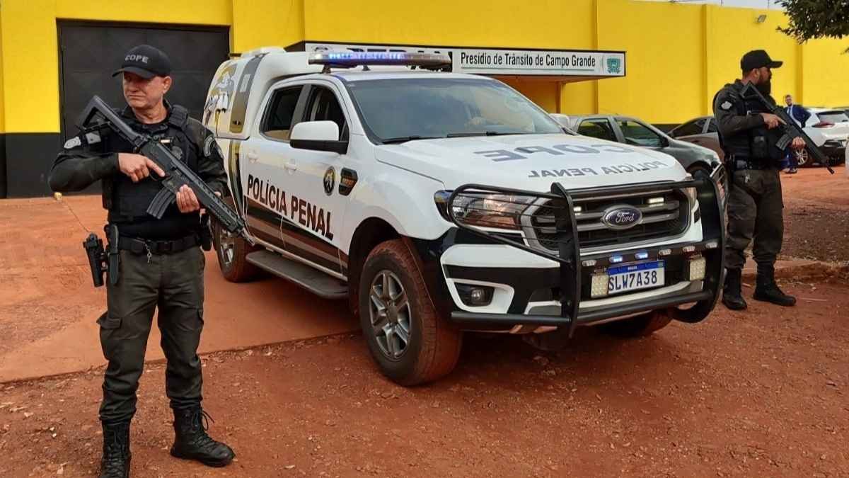PPMS permanece sem regulamentação - Policiais penais armados fazem guarda ao lado de viatura da Polícia Penal em frente ao Presídio de Trânsito de Campo Grande (MS).
