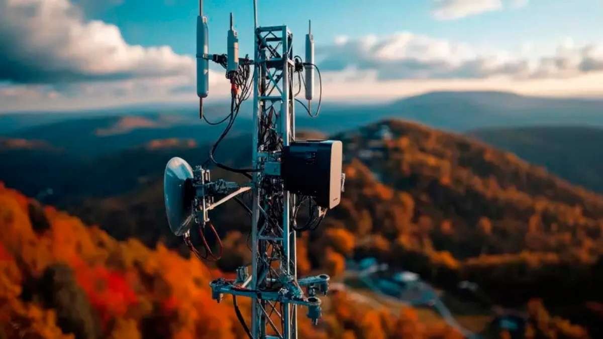 Milícia 5G: Antena de telecomunicações em torre metálica, instalada em área montanhosa com vegetação outonal e vista panorâmica ao fundo.