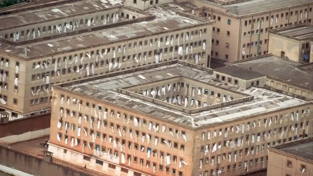 Vista aérea do Complexo Penitenciário do Carandiru, em São Paulo, com várias janelas exibindo lençóis e panos brancos pendurados para fora das celas.