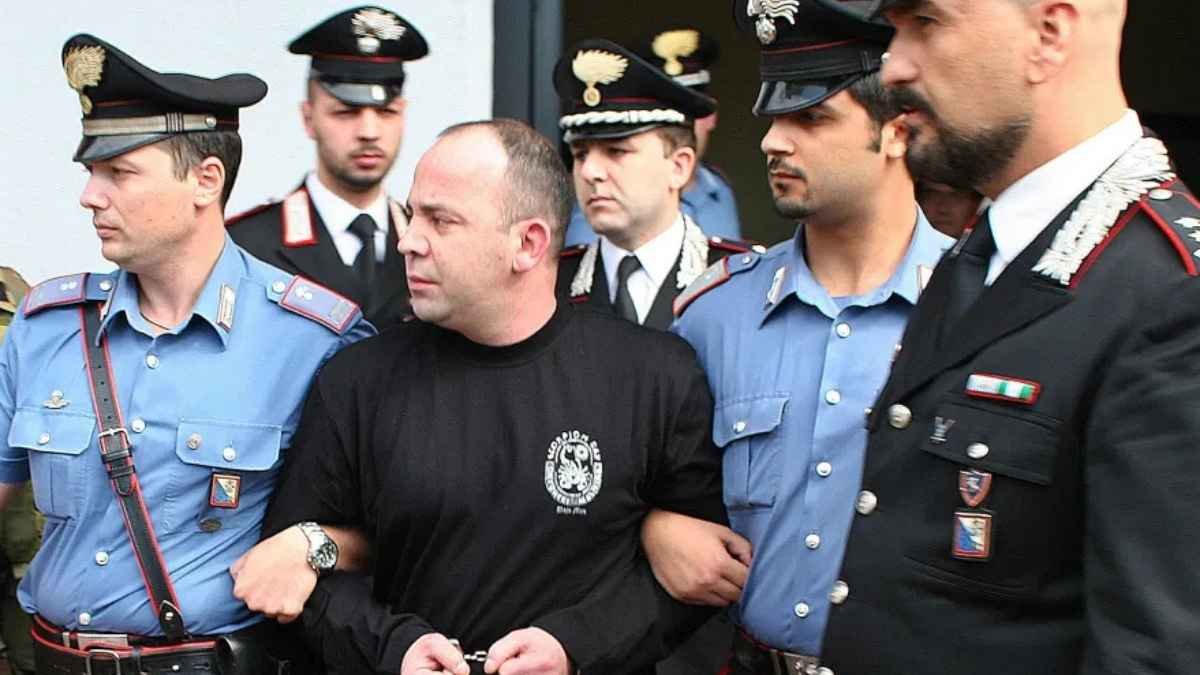 Crime Organizado-Homem algemado é escoltado por vários policiais italianos de uniforme, em operação contra o crime organizado.