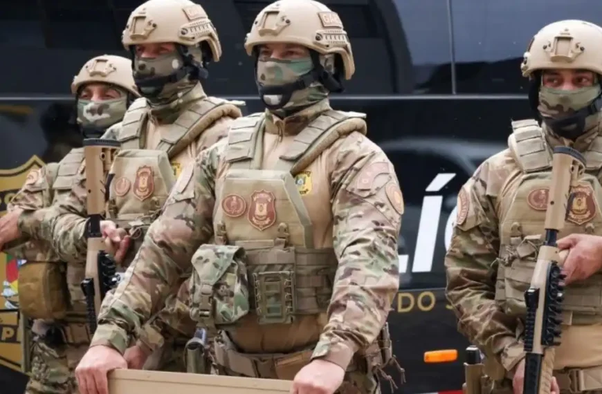 Novo uniforme: PPRS -Homens fardados da Polícia Penal do Rio Grande do Sul, integrantes do Grupo de Ações Especiais (GAES), posam lado a lado usando novos uniformes camuflados em tons de bege e verde, coletes balísticos e capacetes, com armas e equipamentos táticos diante de viatura oficial.