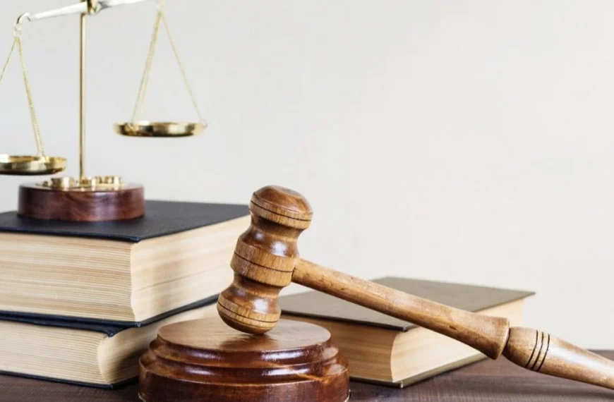 Solto 21 vezes: Martelo de juiz apoiado em base de madeira, ao lado de livros de direito e balança dourada da justiça sobreposta, simbolizando o poder judiciário