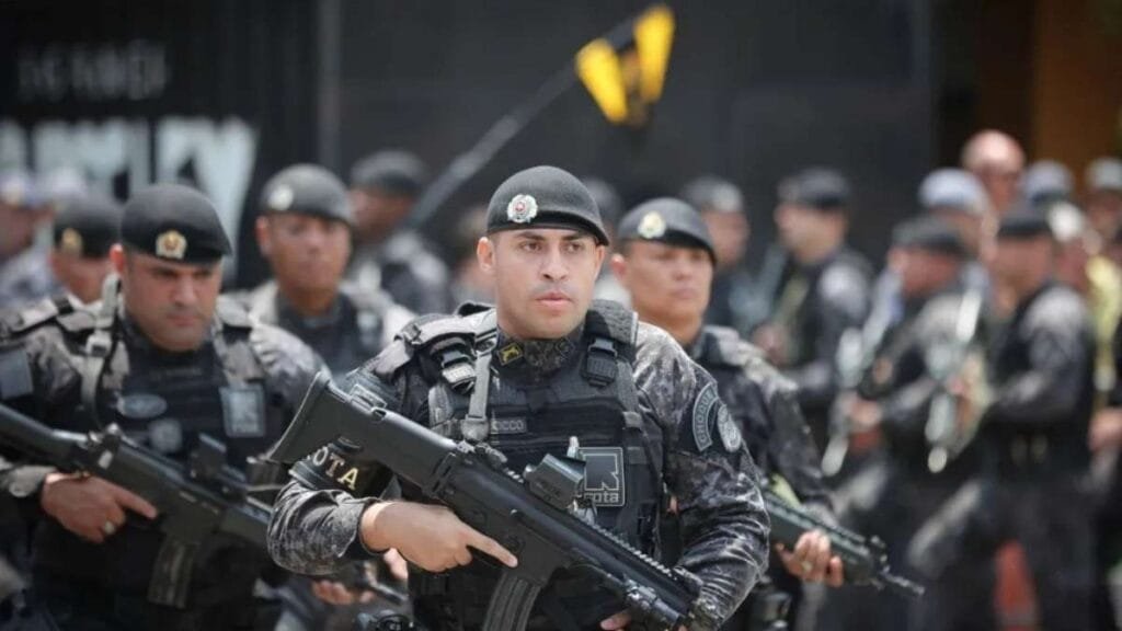 Policiais militares da ROTA, unidade especial da PM de São Paulo, em formação durante operação, equipados com fardamento tático, coletes balísticos e armamento pesado.