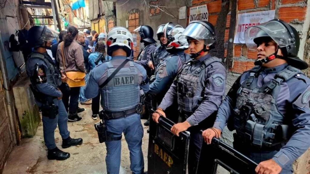 Quem poderia imaginar? Líder de comunidade era do PCC-Policiais militares do BAEP, equipados com escudos e capacetes, fazem operação em viela estreita da Favela do Moinho, onde há imóveis interditados e moradores acompanhando a ação.