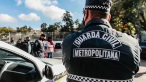 Leniência judicial impede combate ao crime pela GCM-Agente da Guarda Civil Metropolitana, de costas, próximo a uma viatura, acompanha ação em área urbana com outras pessoas e policiais ao fundo.