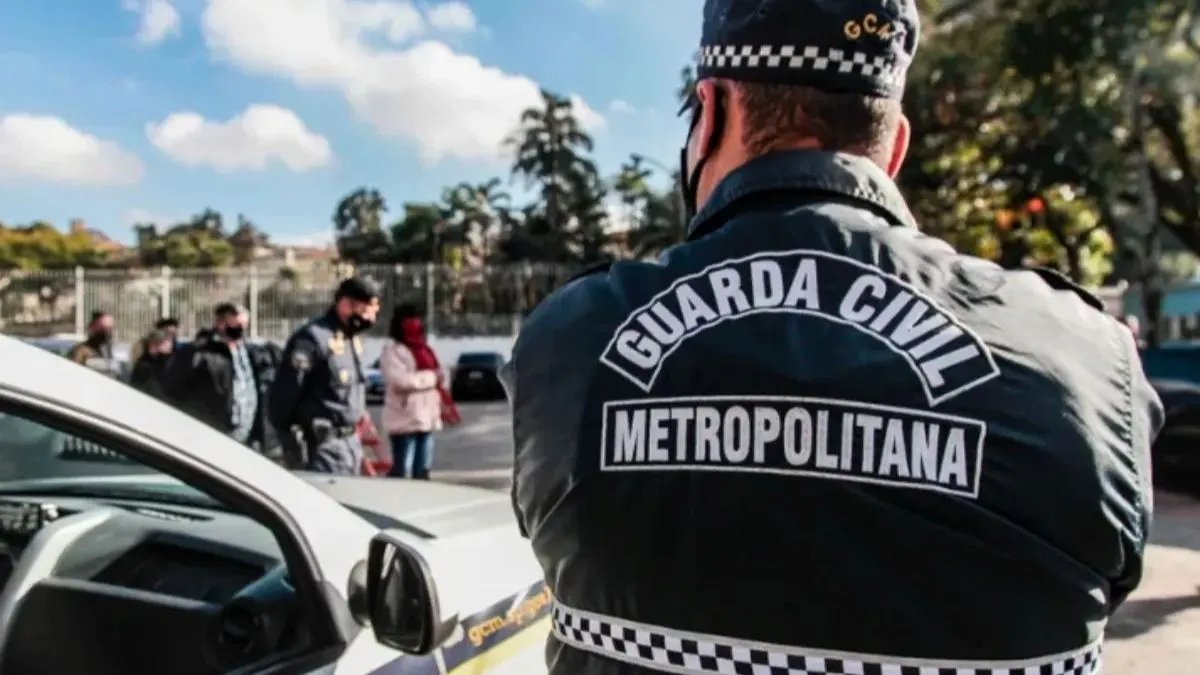 Leniência judicial impede combate ao crime pela GCM-Agente da Guarda Civil Metropolitana, de costas, próximo a uma viatura, acompanha ação em área urbana com outras pessoas e policiais ao fundo.