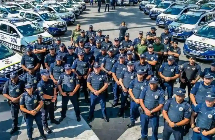 Universidade da GCM-SP-Grupo de guardas civis municipais em formação, posicionados em frente a diversas viaturas oficiais estacionadas lado a lado.