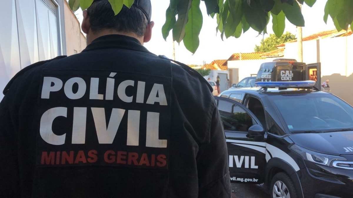 PCMG: sem policiais e sem reajuste-Policial civil de Minas Gerais de costas, com viatura da Polícia Civil estacionada ao fundo em área urbana