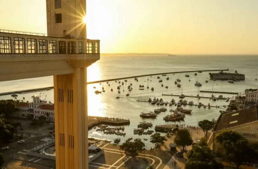 Salvador: cidade mais perigosa do Brasil-A imagem mostra o Elevador Lacerda em Salvador, com vista para a Baía de Todos-os-Santos ao pôr do sol, barcos ancorados e o Mercado Modelo ao fundo.