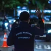 CGM: da vigilância à Polícia Municipal-A imagem mostra um agente da Guarda Municipal de Londrina de costas, usando uniforme azul escuro, com o braço levantado em um gesto de sinalização.
