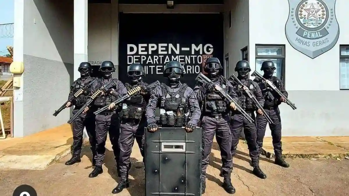 Avanço da terceirização na Polícia Penal-A imagem mostra um grupo de policiais penais fortemente armados e equipados, posicionados em frente a um prédio do Departamento Penitenciário de Minas Gerais (DEPEN-MG).