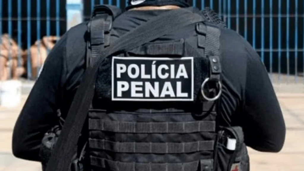 Preso Rondônia PPRO -A imagem mostra um agente de costas vestindo colete tático preto com a identificação “POLÍCIA PENAL” em destaque.