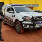 Agentes da Polícia Penal armados ao lado de viatura em unidade prisional, ilustrando desigualdade salarial e estrutura da carreira no Brasil