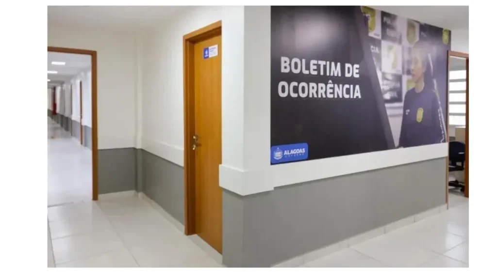 Corredor interno de uma Central de Flagrantes em Alagoas, com portas de atendimento e painel na parede indicando a área de registro de boletim de ocorrência (falsas comunicações de crimes)
