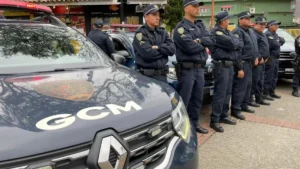 Guardas civis municipais uniformizados estão alinhados ao lado de viaturas da GCM de Ribeirão Pires durante uma formação operacional em via pública.