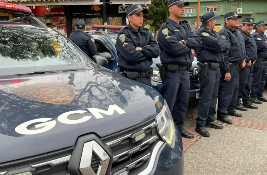 Guardas civis municipais uniformizados estão alinhados ao lado de viaturas da GCM de Ribeirão Pires durante uma formação operacional em via pública.