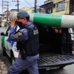 Policiais militares transportam cilindro de oxigênio durante ação de apoio à população em período da pandemia de Covid-19 em área urbana.