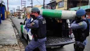 Policiais militares transportam cilindro de oxigênio durante ação de apoio à população em período da pandemia de Covid-19 em área urbana.
