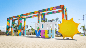 Pórtico colorido de entrada de Porto Velho com a inscrição “Porto Velho” e um sol amarelo estilizado em área urbana da capital de Rondônia. Guarda Municipal de Porto Velho.
