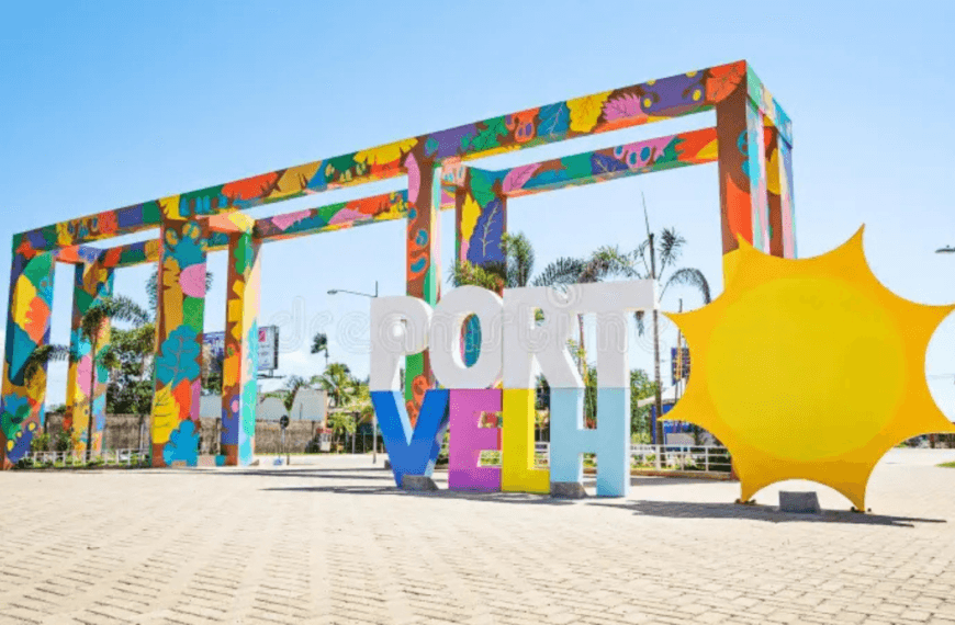Pórtico colorido de entrada de Porto Velho com a inscrição “Porto Velho” e um sol amarelo estilizado em área urbana da capital de Rondônia. Guarda Municipal de Porto Velho.